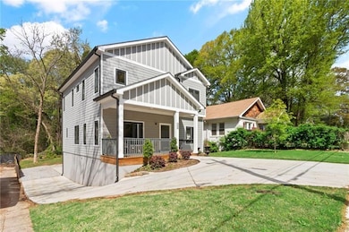 Craftsman-style house featuring covered porch, board and batten siding, and a front lawn