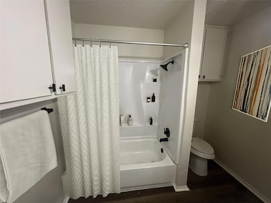 Bathroom with a textured ceiling, toilet, wood fin