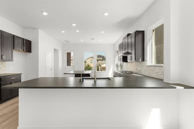 Kitchen featuring tasteful backsplash, dark countertops, recessed lighting, a peninsula, and light wood finished floors
