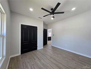 Unfurnished bedroom featuring wood finished floors, recessed lighting, ceiling fan, and a closet