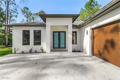 Property entrance with roof with shingles, french doors, stucco siding, and concrete driveway