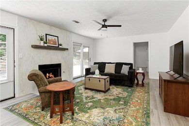 The living room opens up with warmth and intention, featuring a statement fireplace surround and large sliding doors that lead seamlessly to the outdoor patio.