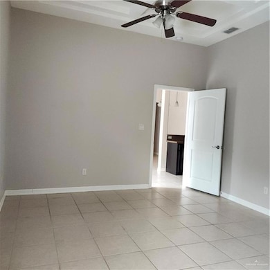 Empty room with light tile patterned floors, ceiling fan, and baseboards
