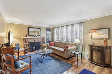 Living room with a fireplace, wood finished floors, and crown molding