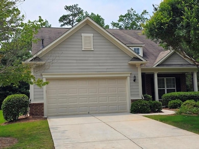 View of front of property featuring brick siding, concrete driveway, a garage, and a shingled roof
