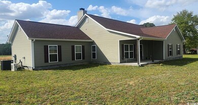 Back of house with a patio, a chimney, a lawn, cen
