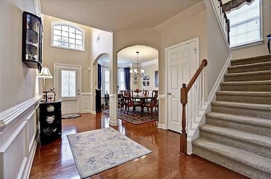 Entrance foyer with arched walkways, stairway, a chandelier, a decorative wall, and a wainscoted wall
