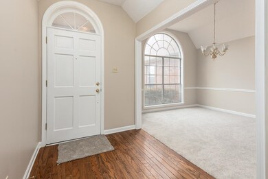 Foyer featuring vaulted ceiling, wood-type floorin