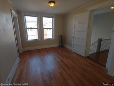 Empty room with wood-type flooring and radiator heating unit