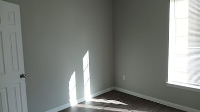 Spare room with baseboards and dark wood-style floors