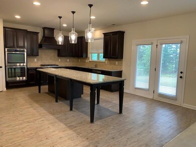 Kitchen featuring tasteful backsplash, custom range hood, recessed lighting, dark brown cabinets, and double oven