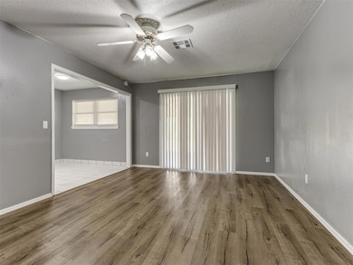 Unfurnished room featuring light wood finished floors, a ceiling fan, and a textured ceiling
