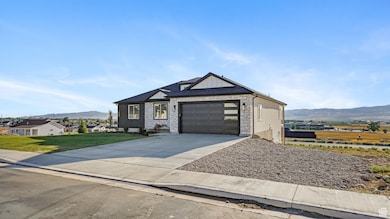 View of front facade featuring a mountain view, driveway, a front lawn, and an attached garage
