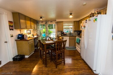 Kitchen with backsplash, dark hardwood / wood-style flooring, and white appliances