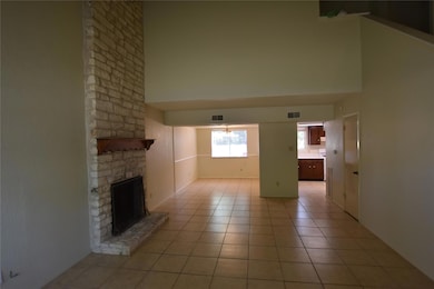 Unfurnished living room featuring a towering ceiling, a fireplace, and light tile patterned ceramic tile floors