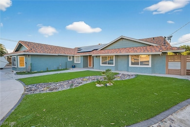 Single story home featuring stucco siding, a front lawn, and solar panels