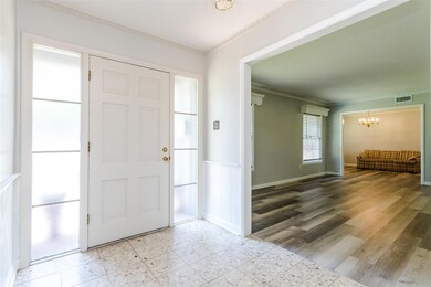 Entryway with a notable chandelier, hardwood / wood-style floors, and crown molding