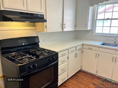 Kitchen with black range with gas stovetop, under cabinet range hood, white cabinetry, and light countertops