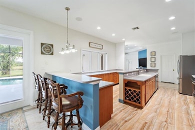 Kitchen with brown cabinets, appliances with stainless steel finishes, a kitchen breakfast bar, a sink, and recessed lighting
