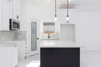 Kitchen with a raised ceiling, white cabinets, a center island, ceiling fan, and tasteful backsplash