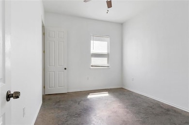 Empty room with baseboards, ceiling fan, and conc