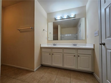 Full bath with double vanity, light tile patterned flooring, and a shower