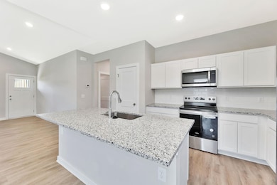 Kitchen includes appliances with stainless steel finishes, granite countertops, LVP floors
