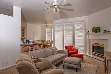 Carpeted living room with a fireplace and a ceiling fan