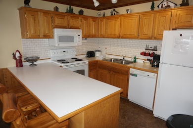 Kitchen with a peninsula, white appliances, a sink