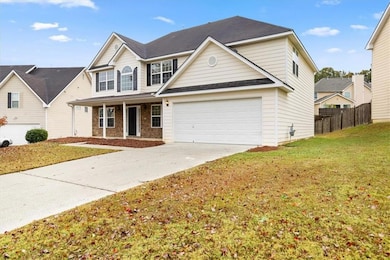 Traditional-style house with a porch, concrete driveway, brick siding, and roof with shingles
