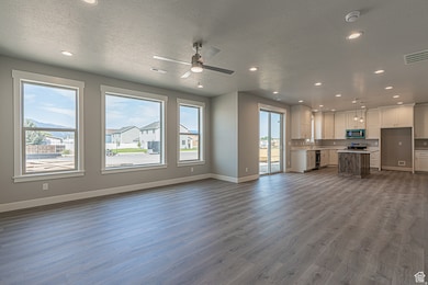 Unfurnished living room with dark wood-style flooring, ceiling fan, a textured ceiling, and recessed lighting