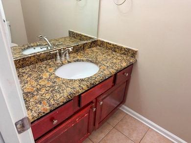 Half bath with baseboards, tile patterned flooring, and vanity