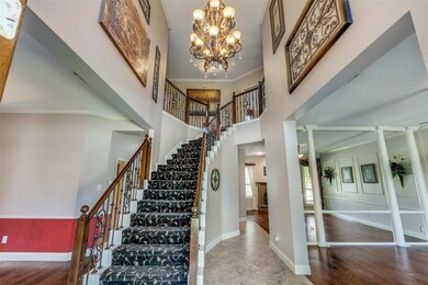 Stairs featuring a notable chandelier, metal spindles, ornamental molding, a towering ceiling, and hardwood / wood-style flooring