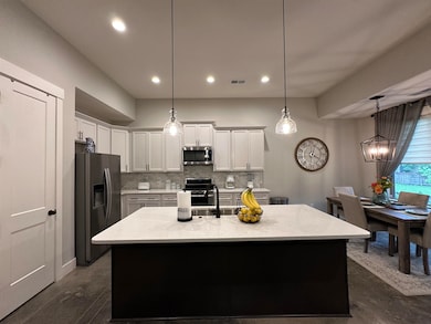 Kitchen featuring appliances with stainless steel finishes, decorative backsplash, a sink, white cabinets, and finished concrete flooring
