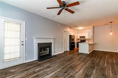 Unfurnished living room featuring a fireplace, dark wood-type flooring, a ceiling fan, and a textured ceiling