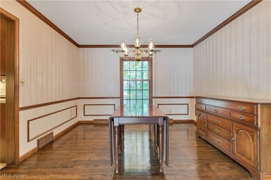 Unfurnished dining area with ornamental molding, dark hardwood / wood-style flooring, and an inviting chandelier