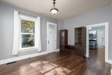 Dining area with dark wood-style flooring and baseboards