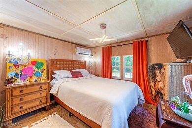 Bedroom featuring a wall unit AC, wood walls, and