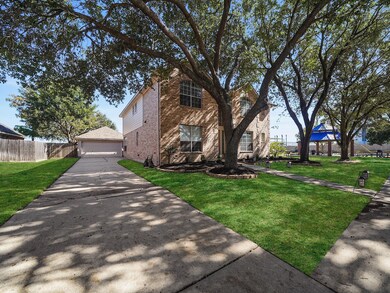 The wide driveway and mature landscaping create an inviting first impression that says “welcome home.”