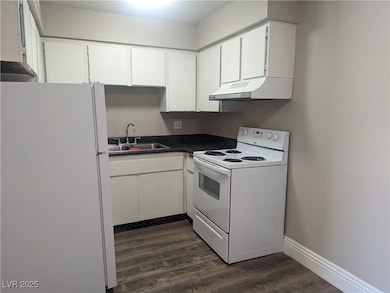 Kitchen with dark countertops, white cabinets, a s
