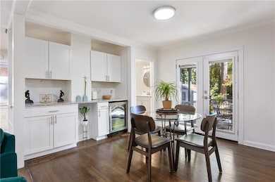 Dining area featuring dark wood-style floors, beverage cooler, crown molding, and french doors