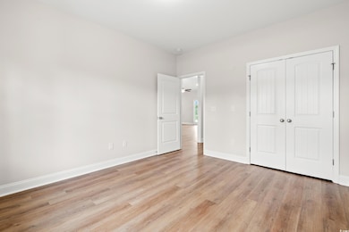 Unfurnished bedroom featuring light wood-type flooring, a closet, and baseboards