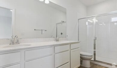 Full bathroom featuring a shower stall, double vanity, and dark wood-style flooring