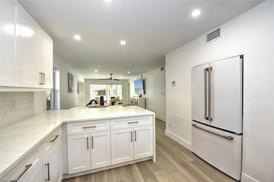 Kitchen featuring high end fridge, a peninsula, ceiling fan, white cabinets, and light wood-type flooring