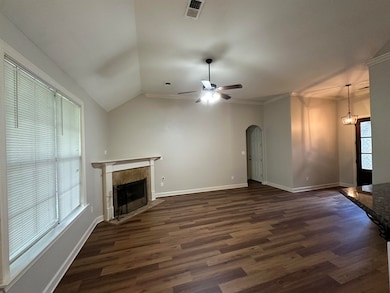 Unfurnished living room with a tiled fireplace, dark wood finished floors, a ceiling fan, arched walkways, and lofted ceiling