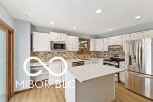 kitchen with light wood-type flooring, light countertops, decorative backsplash, white cabinets, and stainless steel appliances