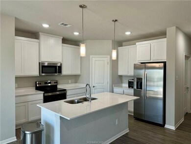 Kitchen with visible vents, white cabinets, a sink