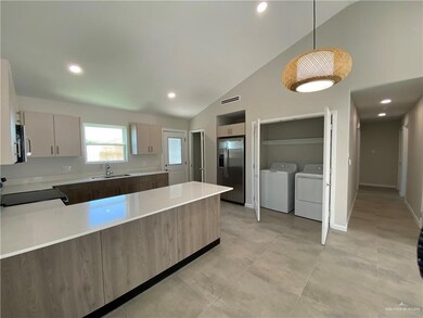 Kitchen featuring lofted ceiling, light tile floors, sink, washer and dryer, and appliances with stainless steel finishes