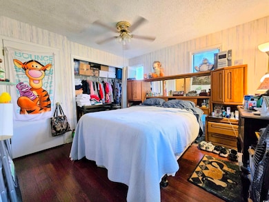 Bedroom with a textured ceiling, a closet, dark wo