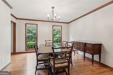 Dining area with plenty of natural light, a chandelier, crown molding, and light wood finished floors